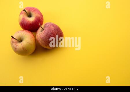 Rote Äpfel nebeneinander auf gelbem Hintergrund angeordnet Stockfoto