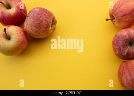 Rote Äpfel nebeneinander auf gelbem Hintergrund. Natürlicher Hintergrund, Fruchtset Stockfoto