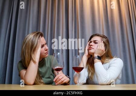 Eine Frau tröstet einen traurigen depressiven Freund, der Hilfe braucht. Depression mit Alkohol-Konzept. Verärgert junge Mädchen mit unglücklichen Gesicht hält ein Glas Wein lo Stockfoto