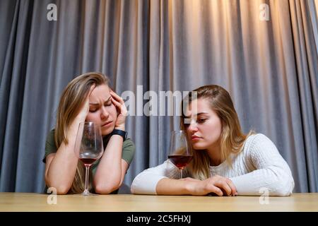 Eine Frau tröstet einen traurigen depressiven Freund, der Hilfe braucht. Depression mit Alkohol-Konzept. Verärgert junge Mädchen mit unglücklichen Gesicht hält ein Glas Wein lo Stockfoto