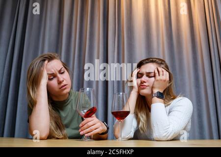 Eine Frau tröstet einen traurigen depressiven Freund, der Hilfe braucht. Depression mit Alkohol-Konzept. Verärgert junge Mädchen mit unglücklichen Gesicht hält ein Glas Wein lo Stockfoto