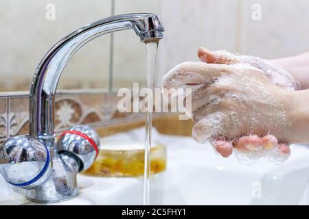Das Mädchen wäscht ihre Hände mit Seife unter dem Wasserhahn mit Wasser. Körperpflege. Desinfektion. Hygienekonzept. Corona Virus Prävention zu stoppen Stockfoto