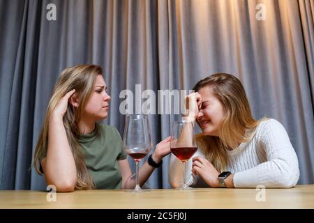 Eine Frau tröstet einen traurigen depressiven Freund, der Hilfe braucht. Depression mit Alkohol-Konzept. Verärgert junge Mädchen mit unglücklichen Gesicht hält ein Glas Wein lo Stockfoto