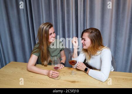 Eine Frau tröstet einen traurigen depressiven Freund, der Hilfe braucht. Depression mit Alkohol-Konzept. Verärgert junge Mädchen mit unglücklichen Gesicht hält ein Glas Wein lo Stockfoto