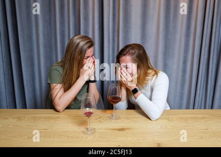 Eine Frau tröstet einen traurigen depressiven Freund, der Hilfe braucht. Depression mit Alkohol-Konzept. Verärgert junge Mädchen mit unglücklichen Gesicht hält ein Glas Wein lo Stockfoto