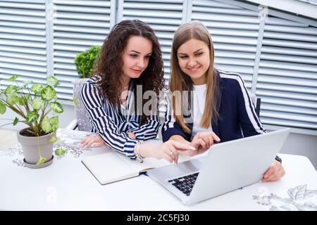 Zwei erfolgreiche junge Geschäftsführerin sitzen mit Laptop und Notebook an einem Tisch und arbeiten an einem neuen Entwicklungsprojekt, Studentinnen Stockfoto