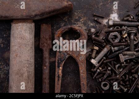 Alte Muttern, Schrauben und Nägel fettig und schmutzig stark verrostet liegen auf dunklem Metallhintergrund Stockfoto