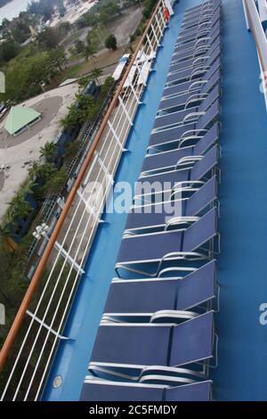 Blaue Lounge-Stühle auf dem Kreuzfahrtschiff, alle in einer Reihe. Mit Schiffsschiene und Decks. Stockfoto