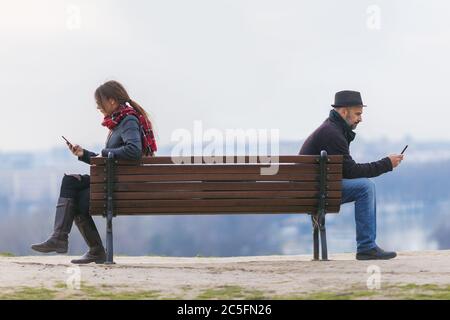 Mann und Frau sitzen auseinander auf einer Parkbank Stockfoto