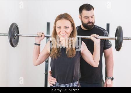 Junge Frau trainiert im Fitnessstudio mit Personal Trainer Stockfoto