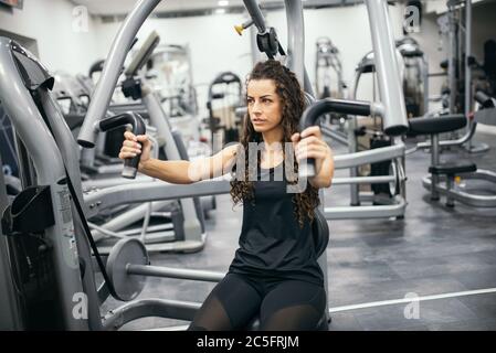 Fokussierte junge schöne Frau macht Übungen im Fitnessstudio. Stockfoto