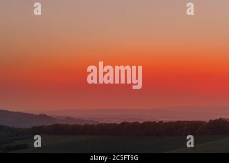 Die untergehende Sonne über der bewaldeten Berglandschaft der Beskiden, die Sonne untergeht über den Horizont. Stockfoto