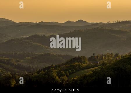 Sonnenaufgang über dem mit Nebel bedeckten Berggebiet dringen orangene Strahlen in die Landschaft ein. Stockfoto