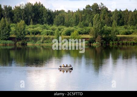 Aufblasbares Motorboot, das auf dem Fluss segelt. Fischer in Tarnung an Bord . Angelsaison, Wilderei, Fischerei-Kontrolle Idee Stockfoto