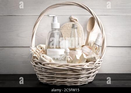 Zusammensetzung von kosmetischen Flaschen und Seife im Korb, auf weißem Holzhintergrund Stockfoto