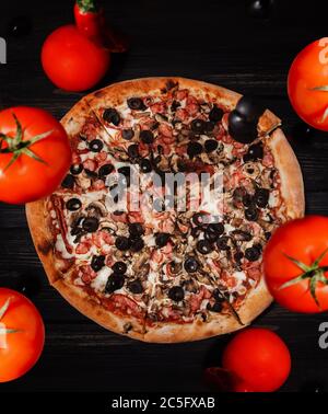 Pizza-Konzept. Pizza gefüllt mit Tomaten, Paprika, Salami und Oliven Stockfoto