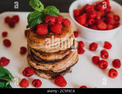 Schokoladen-Pfannkuchen mit frischen Himbeeren und Minze auf schwarzem Hintergrund Stockfoto