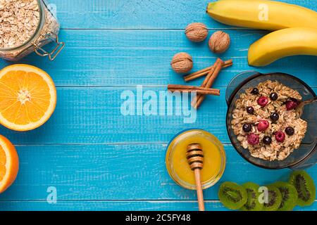 Frühstück mit Haferflocken, Beeren, Honig, Obst und Nüsse. Leerzeichen für Text. Stockfoto