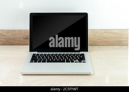 Laptop auf einem Holzschreibtisch mit schwarzem Monitor, um den Inhalt zu finden Stockfoto