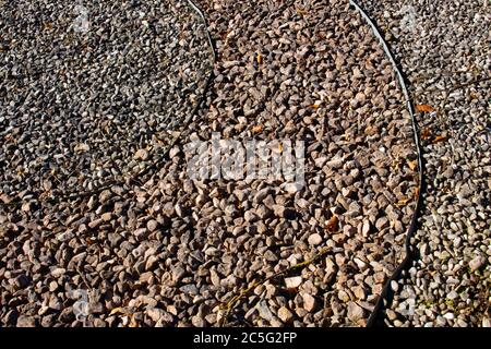 Metalleinkantung, die Schmutz und verschiedene Schotterfarben in einem Park voneinander trennt Stockfoto