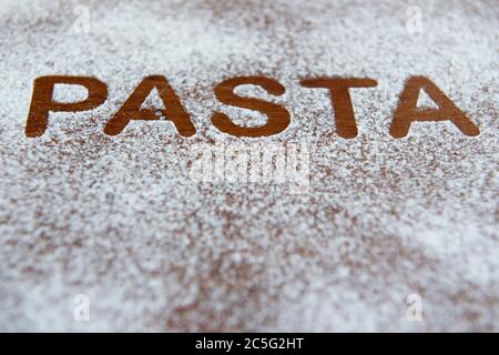 Holzhintergrund mit bestreut Mehl und das Wort Pasta geschrieben. Selektiver Fokus Stockfoto