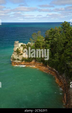 Pictured Rocks National Lakeshore MI / OCT EIN Sonnenfenster beleuchtet das Wasser des Bergarbeiters Castle und die dichten Nadelbäume unter einem Himmel aus Cumuluswolken Stockfoto