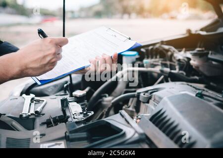 Asian Auto Mechaniker tun eine Checkliste und Notiz Bericht auf Papier Zwischenablage. Stockfoto