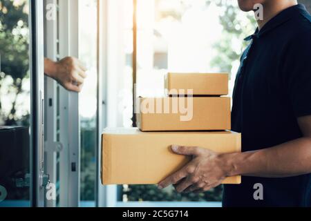Nahaufnahme der Hand Empfänger der Ware öffnet die Haustür, um das Paket vom Zustellpersonal abzuholen. Stockfoto