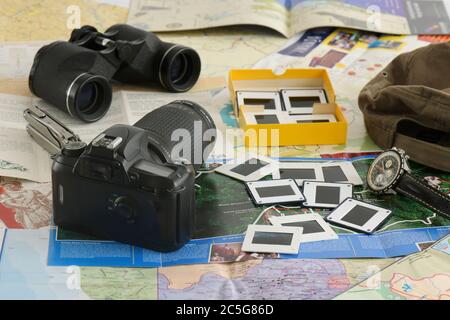 Reiseabenteuer, Konzeptdarstellung, Planung, Vorbereitung, Pilotenuhr, Vintage 35mm Filmkamera, Fernglas, Multitool, Broschüren, Hut, Dias Stockfoto