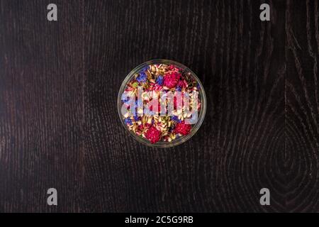 Getrocknete Blumen in einer Glasschüssel - Draufsicht. Auf schwarzem Hintergrund. Stockfoto