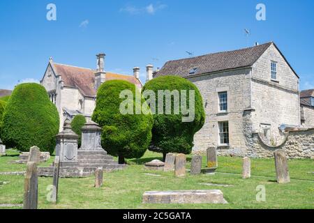 Eibe Bäume und Grabsteine in St. Marys Kirchhof in der Sonne. Painswick, Cotswolds, Gloucestershire, England Stockfoto