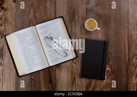 CHICAGO IL US 01 JULY 2020: Offene Bibel auf einem Holztisch liegend bei einer Lesung der Heiligen Bibel mit einer Tasse Kaffee Stockfoto