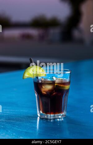 Rum Cola Casual Cocktail mit Eiswürfeln und Limette im Sommer Bar stehen Hintergrund. Stockfoto