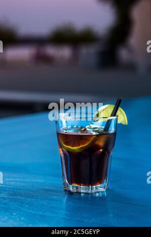 Rum Cola Casual Cocktail mit Eiswürfeln und Limette im Sommer Bar stehen Hintergrund. Stockfoto
