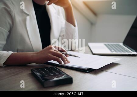 Frauen sitzen und analysieren den Bilanziellen Plan des Unternehmens mit einem Rechner auf seinem Schreibtisch. Stockfoto