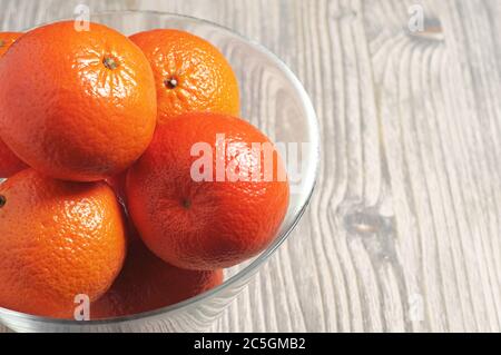 Reife Mandarinen in Glasschale auf rustikalem Holztisch Stockfoto