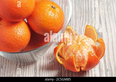 Reife Mandarinen in Glasschale auf rustikalem Holztisch Stockfoto