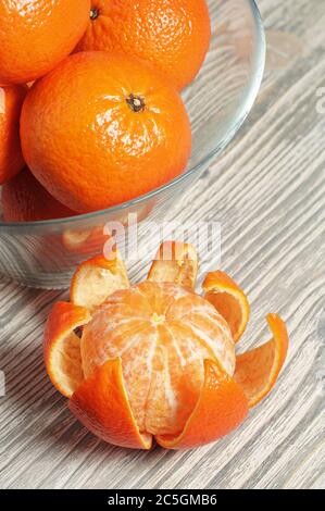 Reife Mandarinen in Glasschale auf rustikalem Holztisch Stockfoto