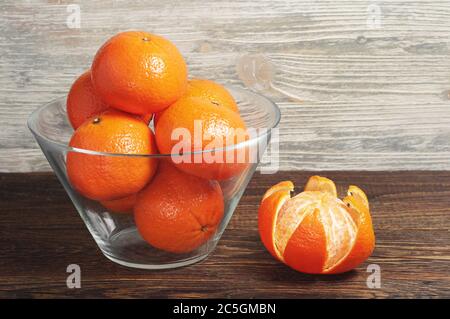 Reife Mandarinen in Glasschale auf rustikalem Holztisch Stockfoto