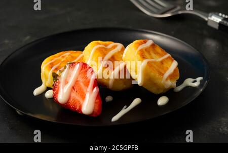 Quark, süße Käsekuchen auf dunklem Hintergrund, mit Erdbeerbeeren, Restaurant serviert Stockfoto