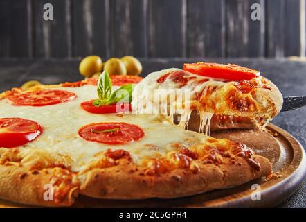 Der köstliche Geschmack von Pizza und Käsescheiben mit Mozzarella und Tomaten. Dreieckspizza mit Stretching-Käse und Gewürzen. Platz für Text kopieren. Stockfoto