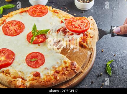 Der köstliche Geschmack von Pizza und Käsescheiben mit Mozzarella und Tomaten. Dreieckspizza mit Stretching-Käse und Gewürzen. Stockfoto