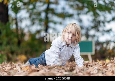 Kleiner blonder Junge posiert draußen Stockfoto