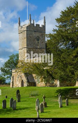 St. Andrew's Pfarrkirche im Dorf Kingham in der Cowswold UK mit Grabsteinen auf dem Friedhof Stockfoto