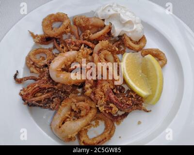 Gebratene Calamari Ringe mit Sauce und Zitrone, leckere Tintenfische, Oktopus Stockfoto