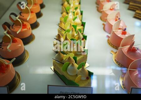 Verschiedene Geschmack bunte eclair und Französisch Gebäck Bäckerei in Glas Vitrine Box angezeigt Stockfoto