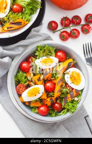 Gemüsesalat mit gegrillter Karotte, Kirschtomaten, Kürbis, Salat, gekochten Eiern und Sesamsamen. Stockfoto