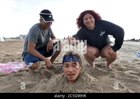 New York City, USA. Juli 2020. Antonio Argueta sitzt am ersten Tag der Wiedereröffnung der New York City Beaches, im Brooklyn Bezirk New York City, NY, am 1. Juli 2020, in einer Sandgrube, die bis zu seinem Hals auf Coney Island vergraben ist. Während der zweiten Phase der Wiedereröffnung von New York City während der COVID-19 Pandemie dürfen die Menschen an die Strände der Stadt zurückkehren, aber die Restaurants im Restaurant wurden aufgrund der landesweiten Zunahme von Coronavirus-Fällen verzögert. (Anthony Behar/Sipa USA) Quelle: SIPA USA/Alamy Live News Stockfoto