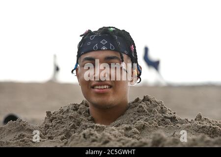 New York City, USA. Juli 2020. Antonio Argueta sitzt am ersten Tag der Wiedereröffnung der New York City Beaches, im Brooklyn Bezirk New York City, NY, am 1. Juli 2020, in einer Sandgrube, die bis zu seinem Hals auf Coney Island vergraben ist. Während der zweiten Phase der Wiedereröffnung von New York City während der COVID-19 Pandemie dürfen die Menschen an die Strände der Stadt zurückkehren, aber die Restaurants im Restaurant wurden aufgrund der landesweiten Zunahme von Coronavirus-Fällen verzögert. (Anthony Behar/Sipa USA) Quelle: SIPA USA/Alamy Live News Stockfoto