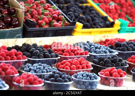 Himbeeren, Heidelbeeren und Brombeeren auf dem Markt in Plastikschalen. Obst-Muster. Stockfoto